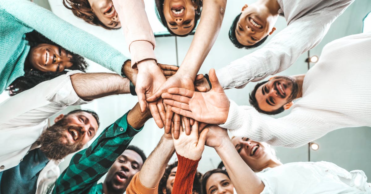 Un gruppo di persone che uniscono le mani, simbolo di inclusione in azienda