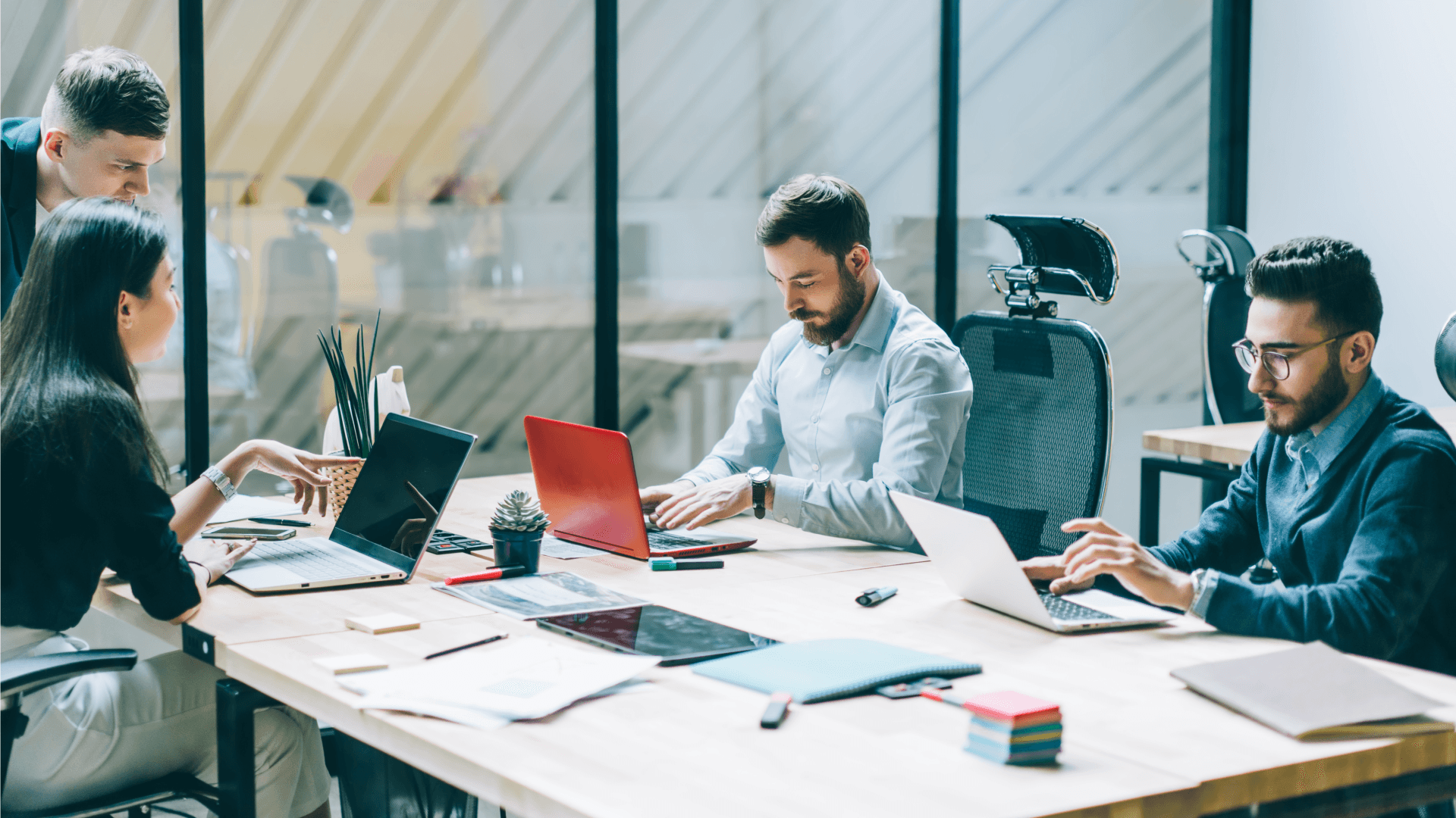 Quattro persone in ufficio intente a lavorare sedute alla scrivania, davanti al computer