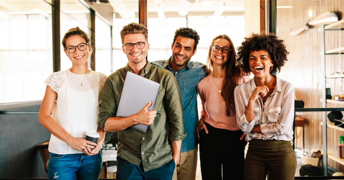 Cinque colleghi in ufficio felici e sorridenti